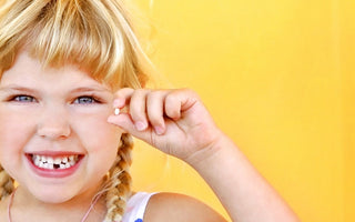 Happy,  blond Child holding tooth and smiling bright
