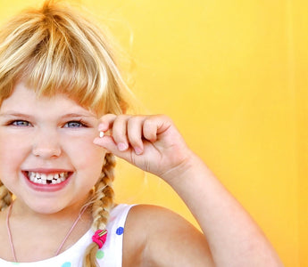 Happy,  blond Child holding tooth and smiling bright